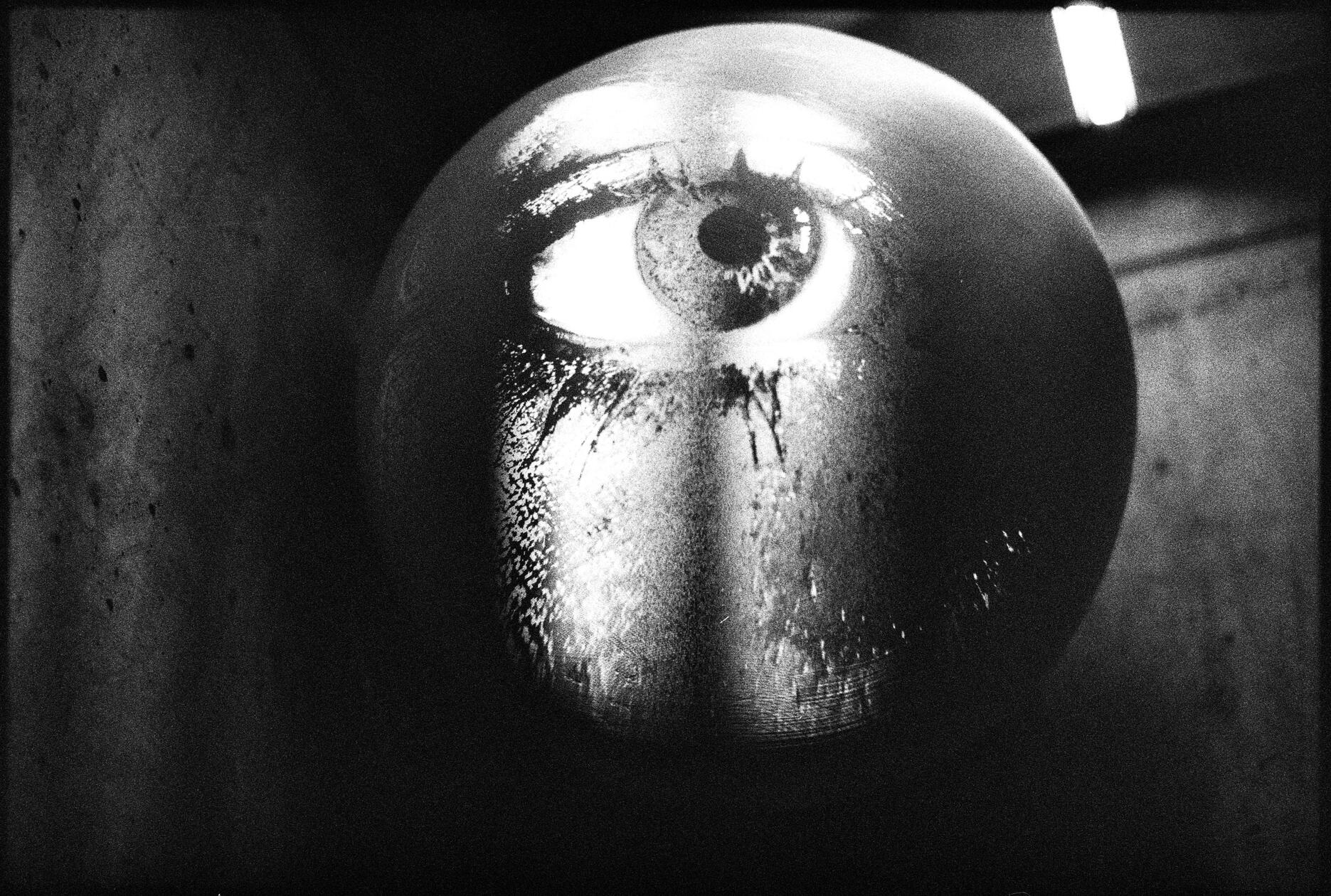 Surreal analog photo of sculptural eye installation, captured with Nikon F2 on Ilford Delta 3200 black and white film.